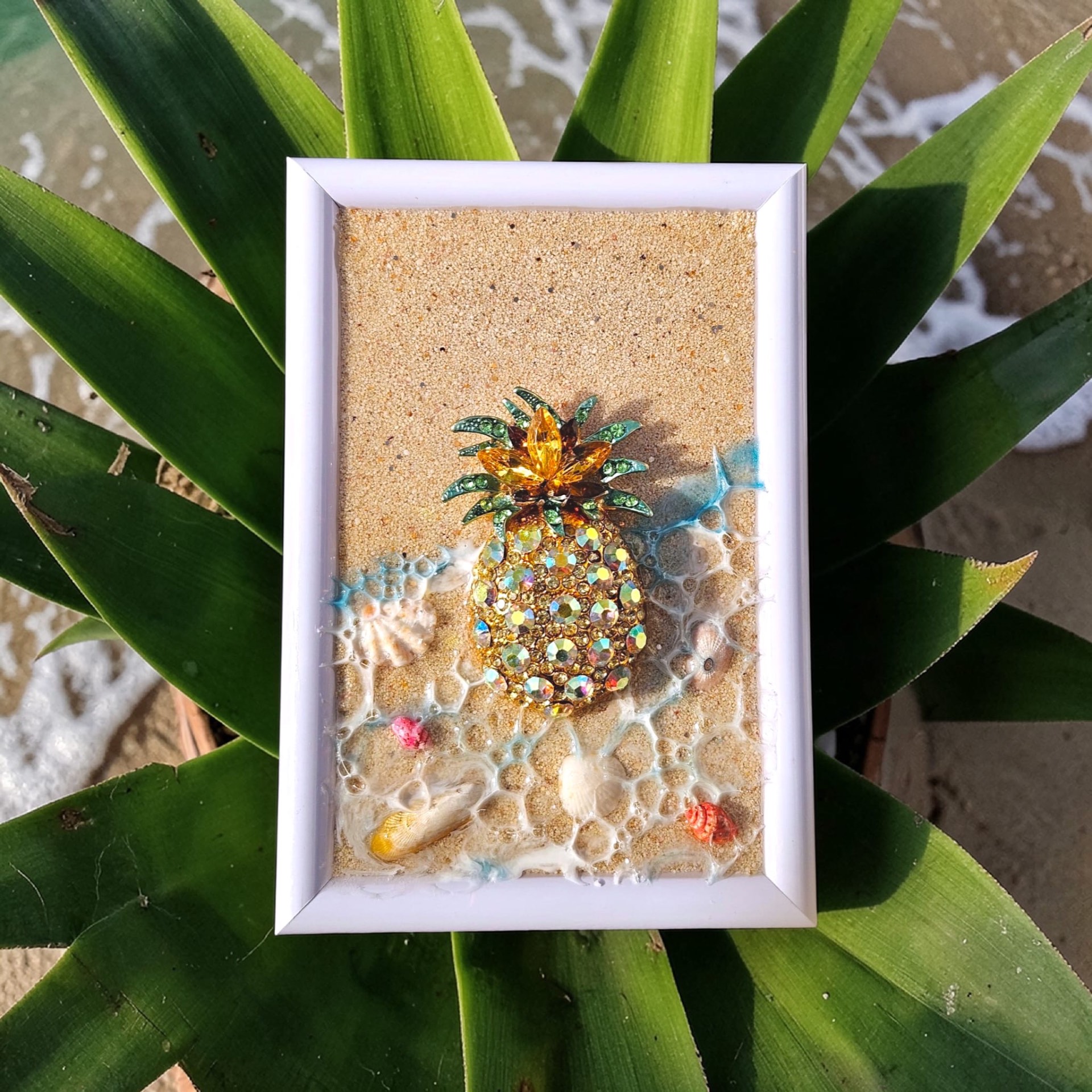 White frame with sand, resin surf, and a jeweled gold pineapple centerpiece.