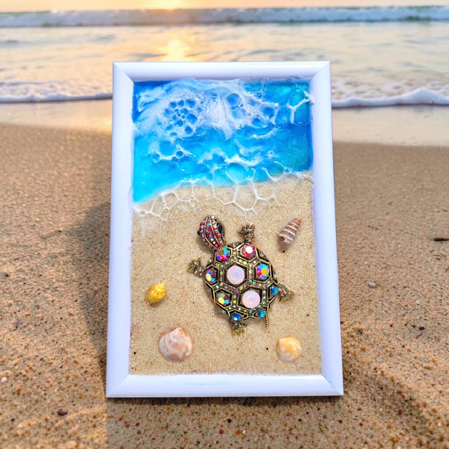White frame with a blue ocean resin scene and a sparkling jeweled sea turtle on sand.