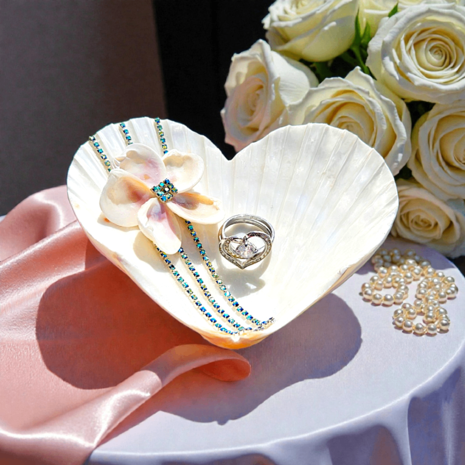 Heart-shaped shell ring dish with a floral embellishment and blue rhinestones.