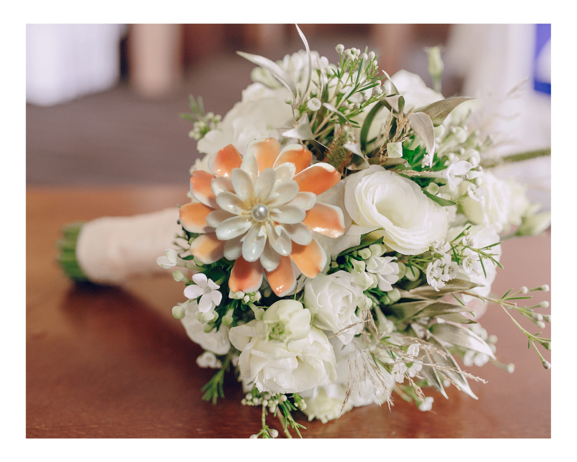 White bridal bouquet with a peach shell flower centerpiece and soft greenery.